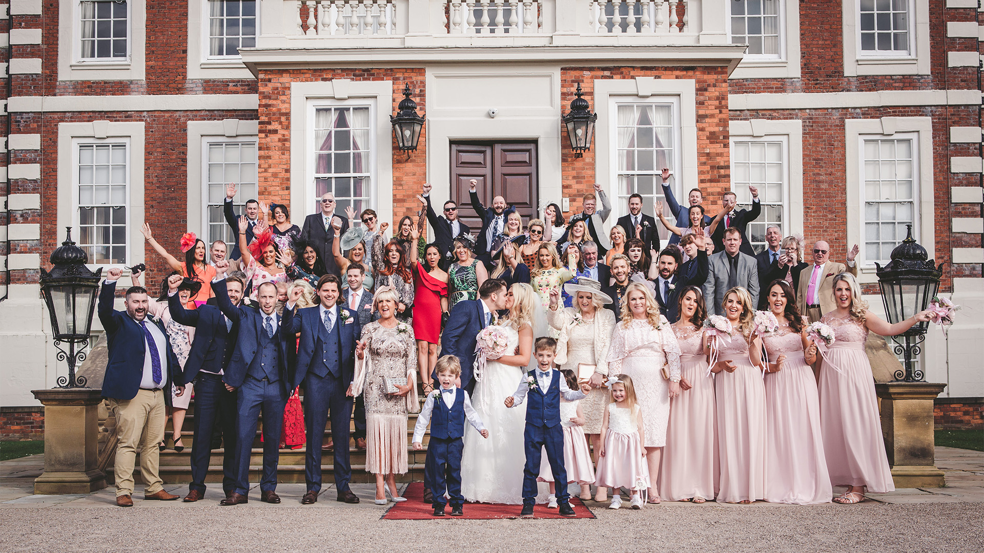 Wedding guests standing outside Knowsley Hall for wedding photographs