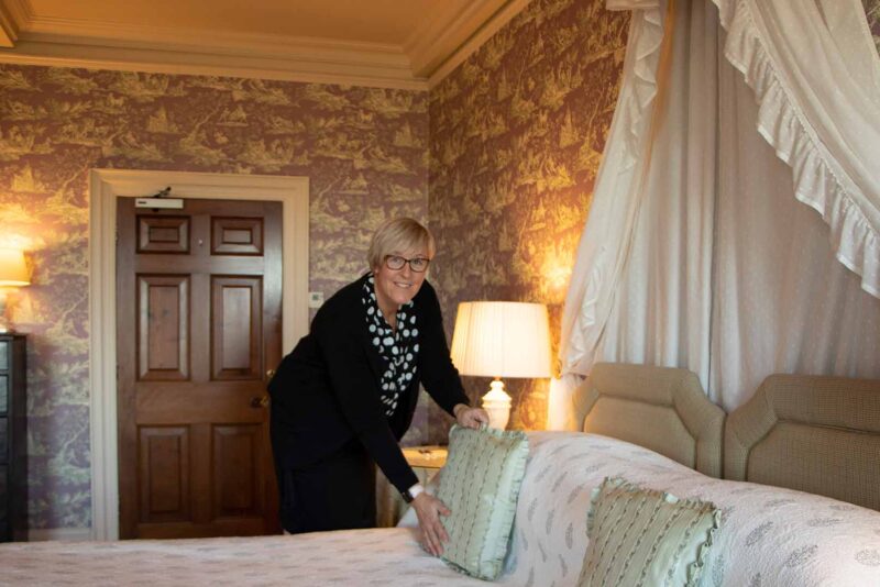 A housekeeper making the bed at Knowsley Hall