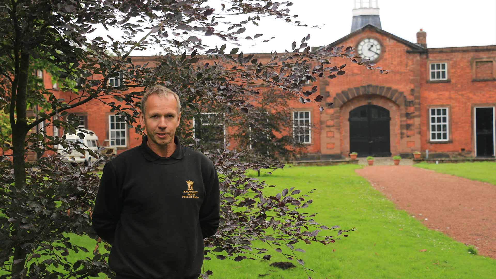 A gardener standing by a building in the Knowsley Estate