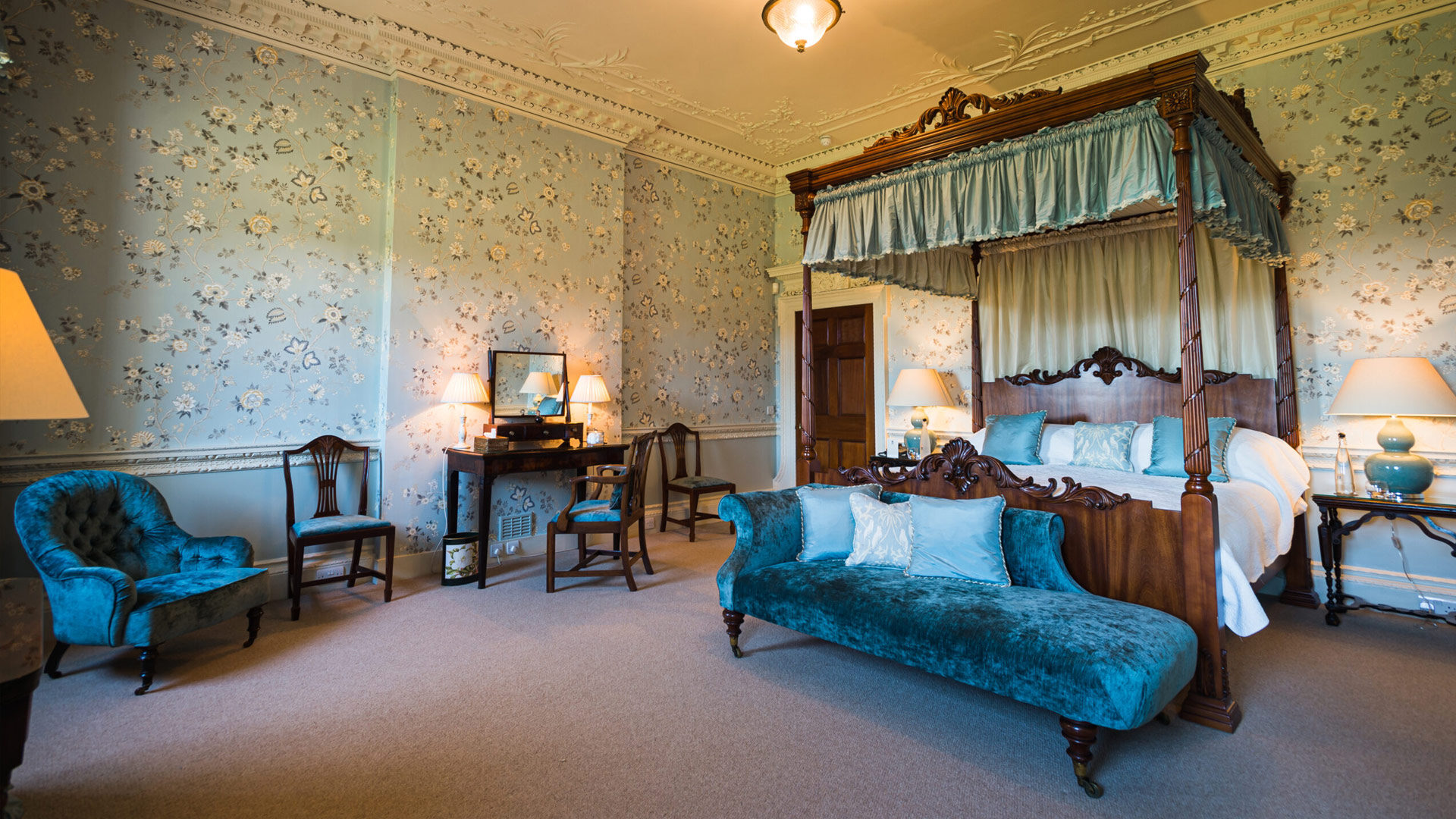 Beautiful and spacious bedroom decorated in blue colours with a four poster bed, chaise lounge, dressing table and chairs at Knowsley Hall