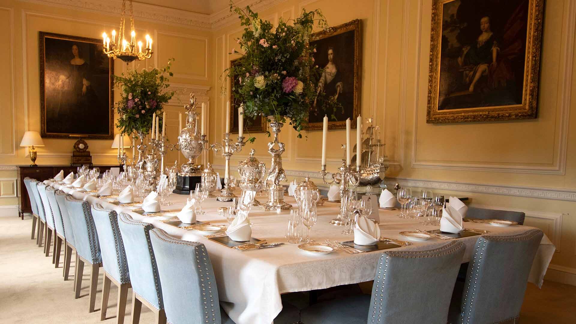 Private and intimate dining room with Long dining table with blue chairs dressed for an elegant banquet with beautiful flowers displayed in a candelabra