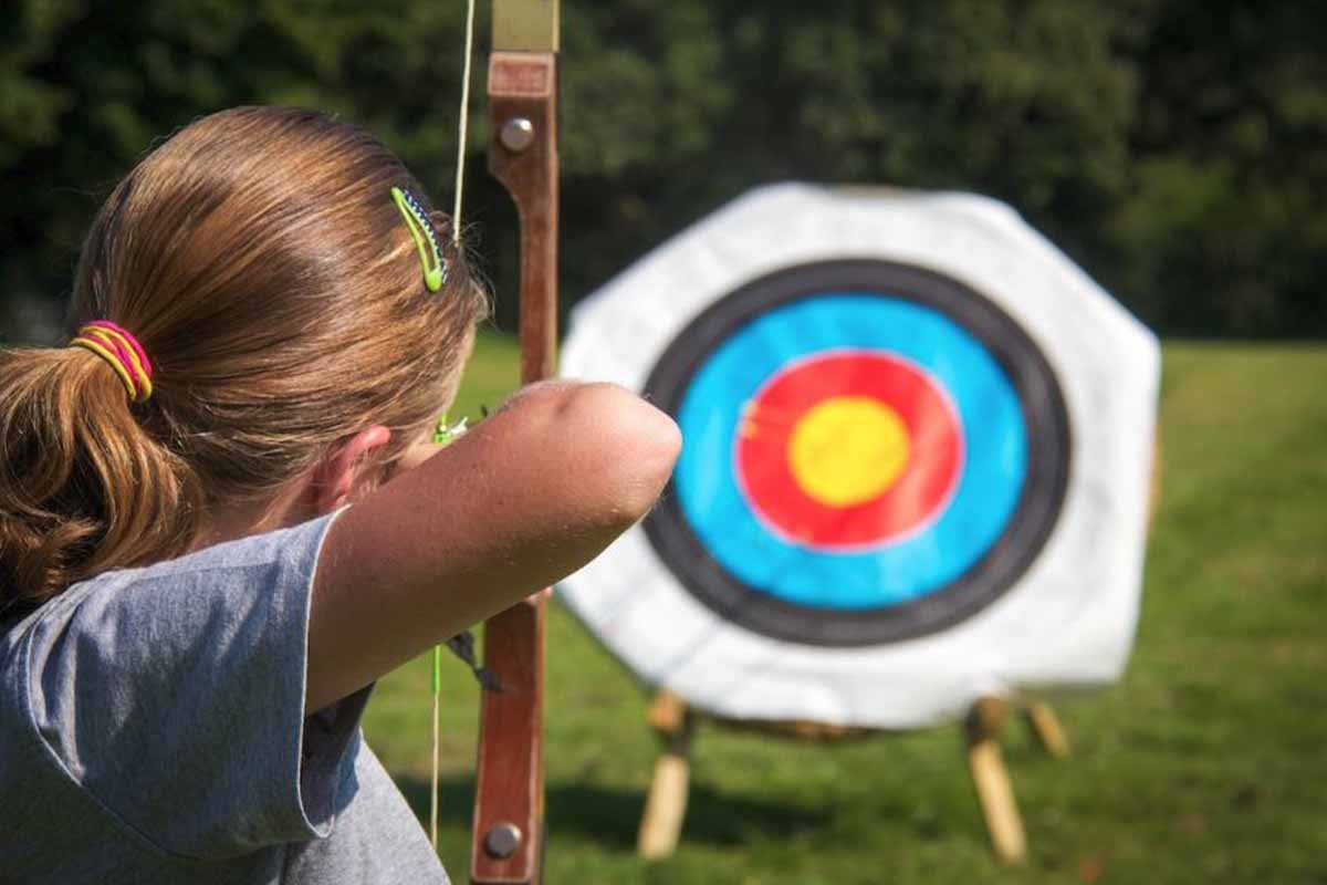 Woman doing archery during a teambuilding day in the grounds of Knowsley Hall