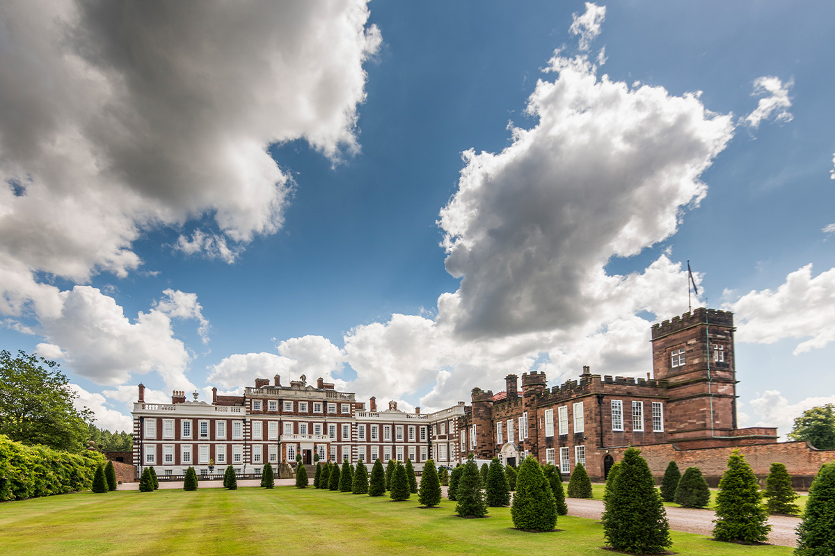 Wide angle view of Knowsley Hall and the front gardens leading up to it with topiary trees lining the drive.