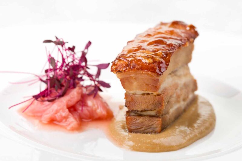 A food picture of a piece of pork with crackling on a plate