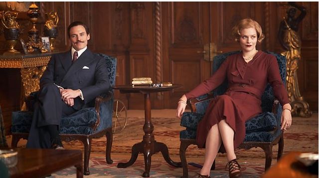 A male and female actor sitting in the Walnut Drawing Room at Knowsley hall filming for Peaky Blinders.