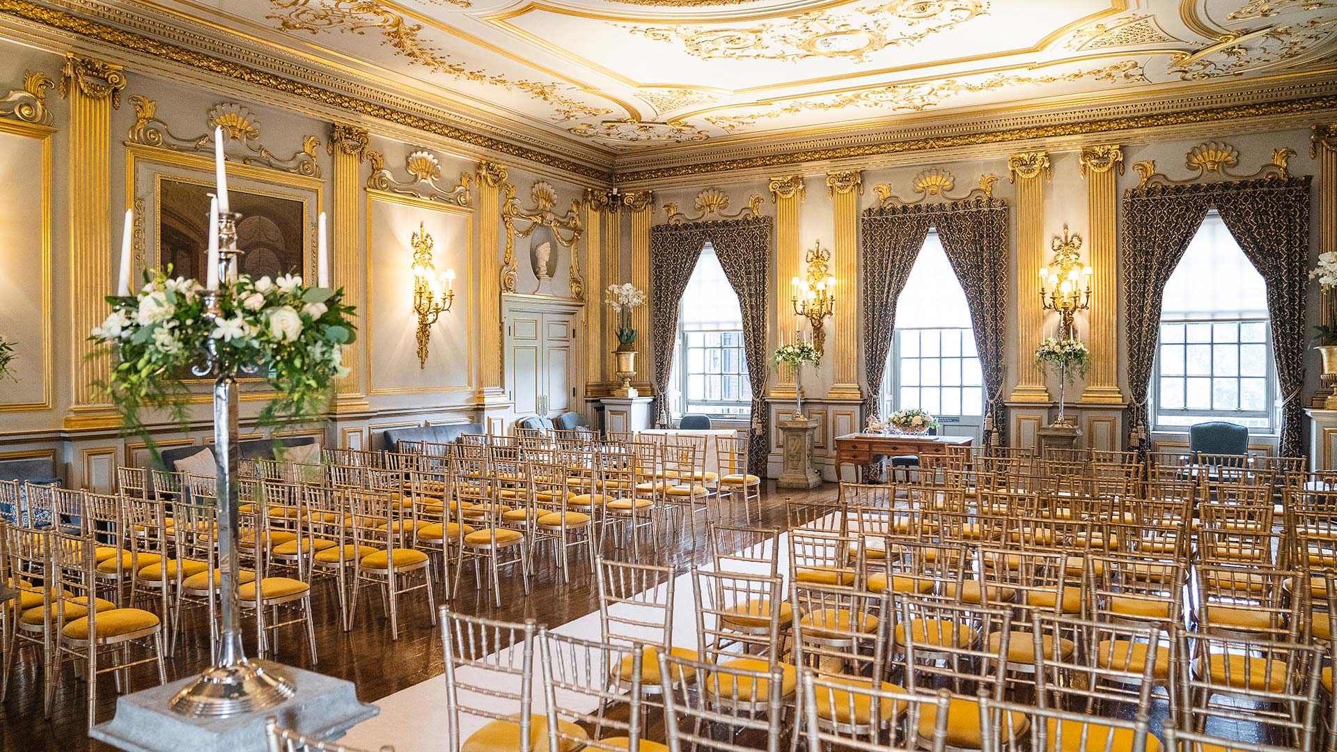 Stunning gold decor room set for a wedding ceremony with chairs and fresh wedding flowers